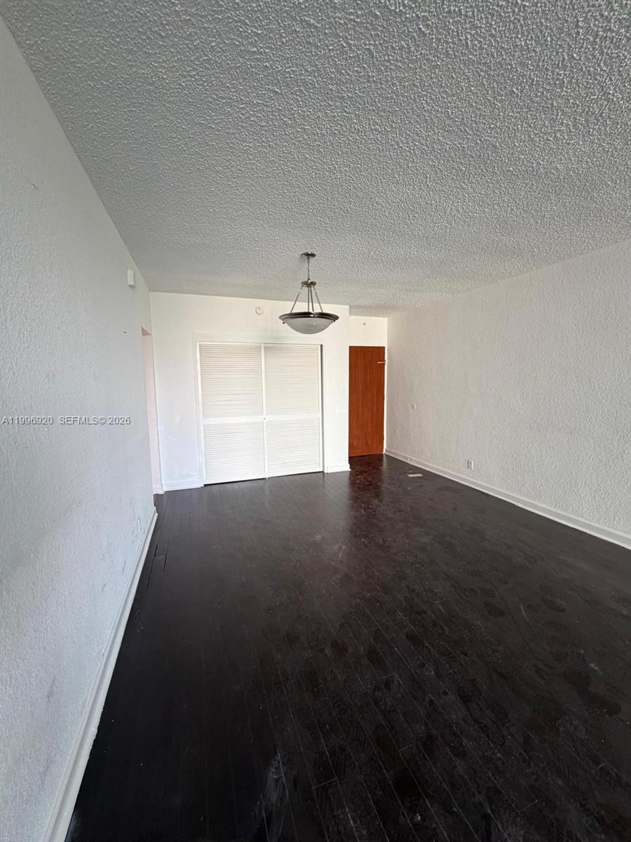 A room with dark wood flooring, white walls, a textured ceiling, and a closet — 4001 S Ocean Dr # 4H, Hollywood FL 33019, HOLLYWOOD, FL