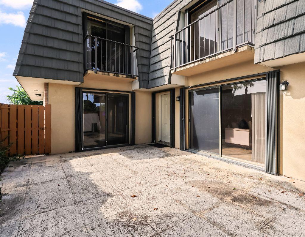 A concrete patio sits in front of a two-story building with sliding glass doors and balconies — 2229 22nd Way, West Palm Beach FL 33407, WEST PALM BEACH, FL