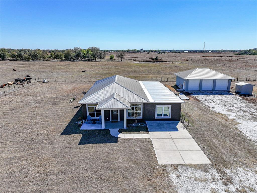 An aerial view shows a single-story house with a metal roof and a detached garage — 2481 NE FAYE TERRACE, ARCADIA, FL