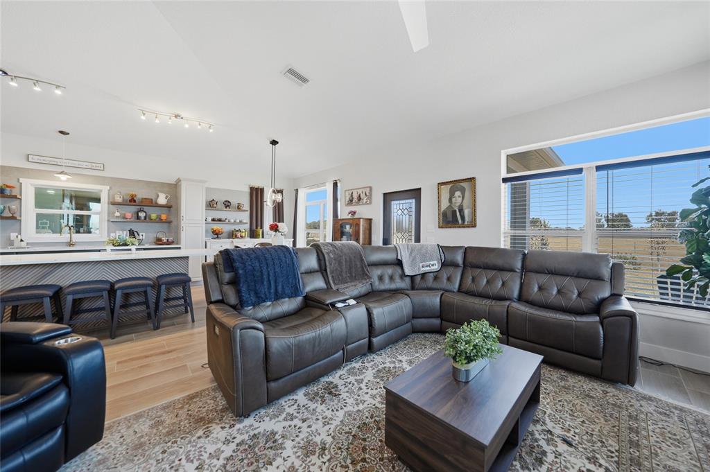 A living room with a dark leather sectional sofa faces a kitchen with bar seating — 2481 NE FAYE TERRACE, ARCADIA, FL