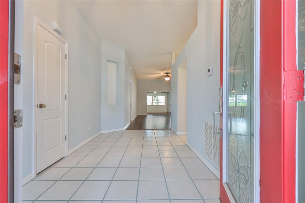 A tiled entryway leads into a home with light blue walls and a distant view — 951 VILLEROY GREENS DRIVE, SUN CITY CENTER, FL