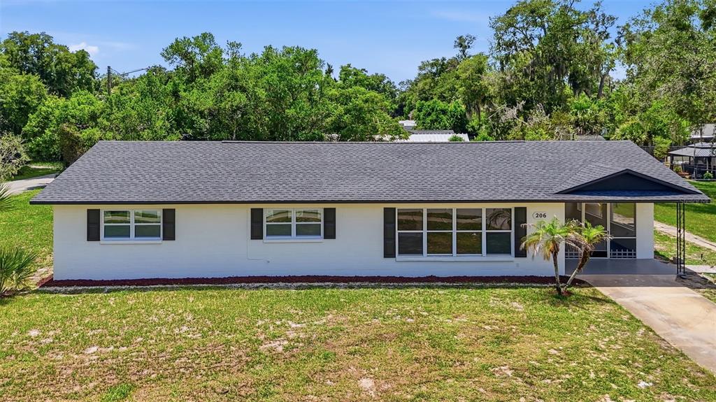 A single-story white house with a dark shingled roof and black window shutters — 206 MARGARITA ROAD, DEBARY, FL