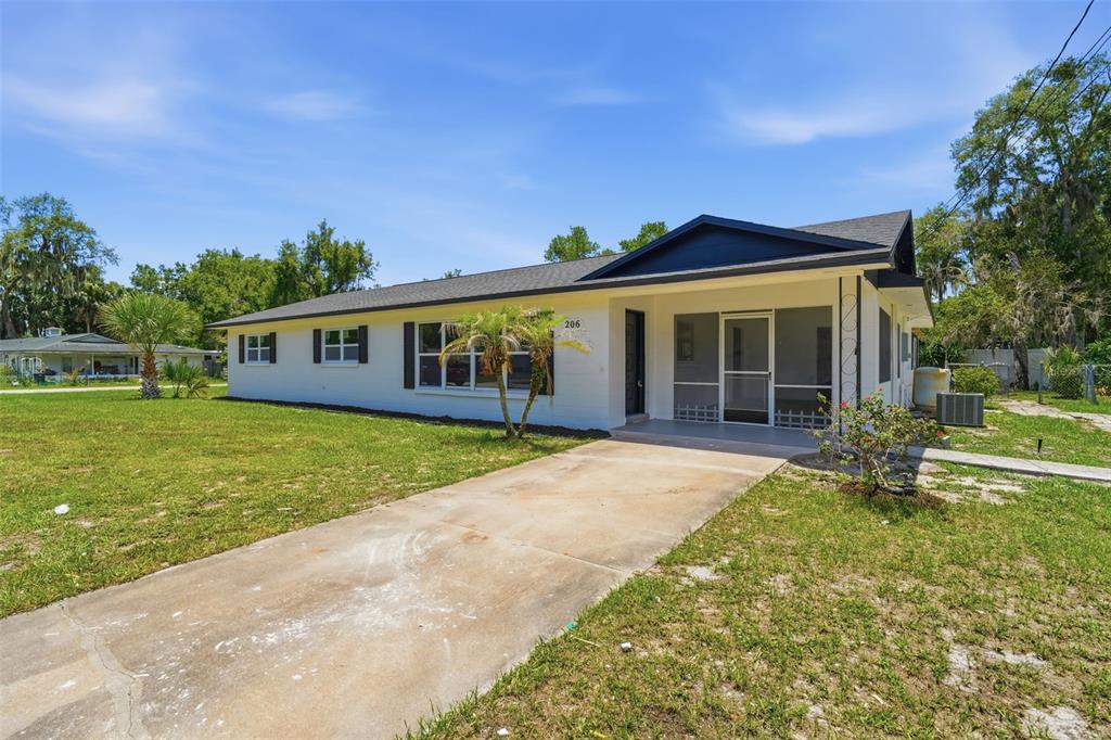 A white single-story house with a dark roof and a concrete driveway — 206 MARGARITA ROAD, DEBARY, FL