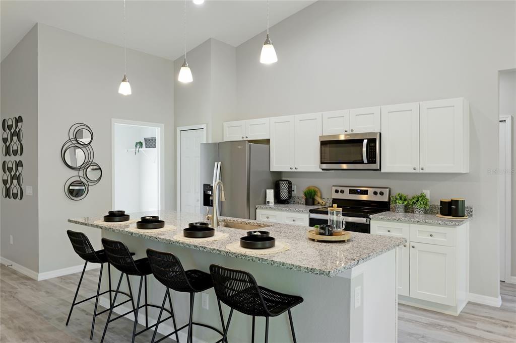 A kitchen features white cabinets, granite countertops, stainless steel appliances, and a breakfast bar island — 4450 WALL LANE, NORTH PORT, FL