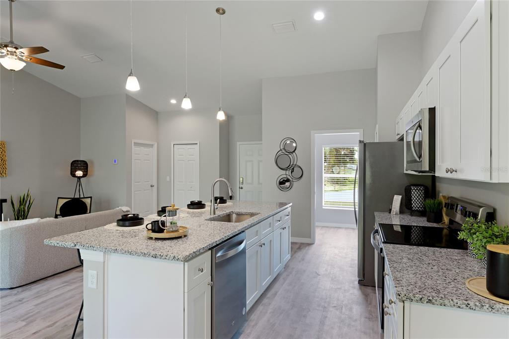 A kitchen features white cabinets, granite countertops, a center island, and stainless steel appliances — 4450 WALL LANE, NORTH PORT, FL
