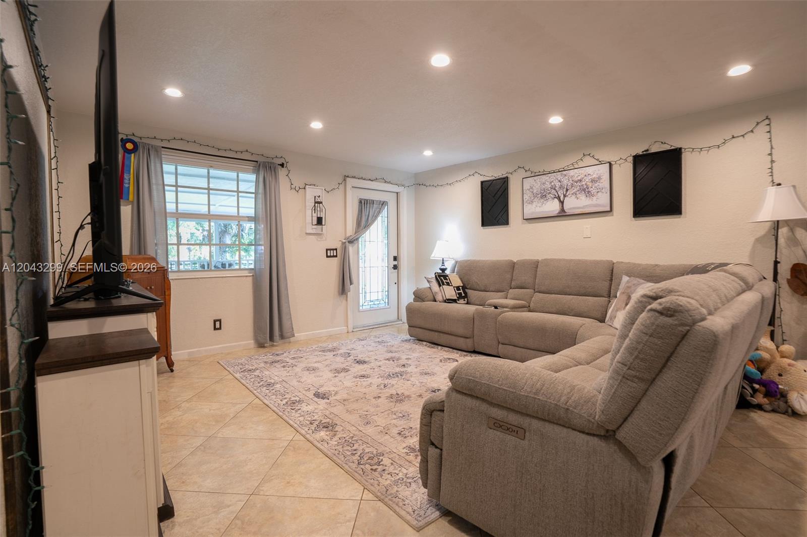 A living room features a gray sectional sofa, a patterned area rug, and tile flooring — 15160 Scotts Pl, Loxahatchee FL 33470, LOXAHATCHEE, FL