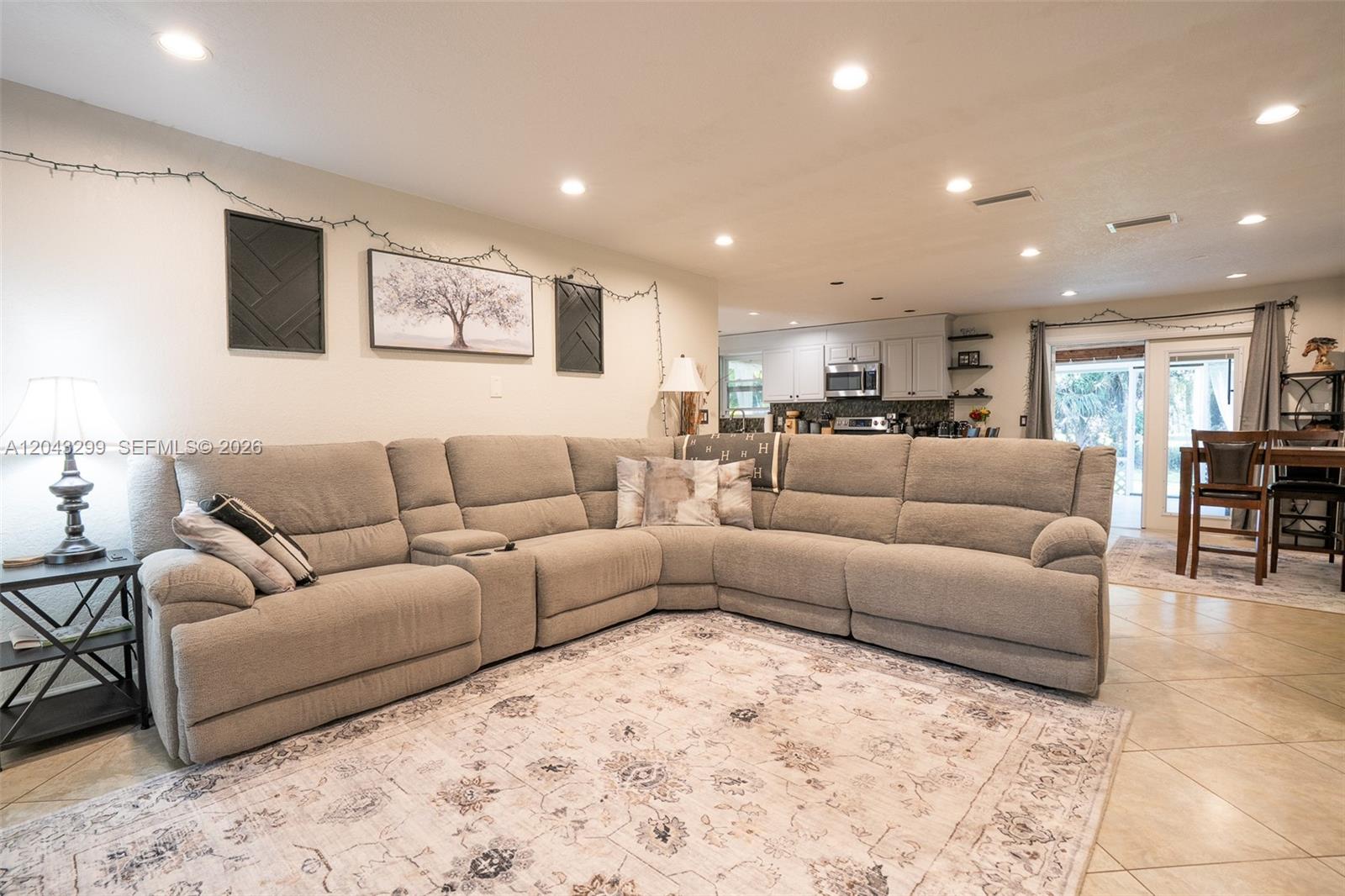 A living room features a large sectional sofa, a patterned area rug, and an open kitchen — 15160 Scotts Pl, Loxahatchee FL 33470, LOXAHATCHEE, FL