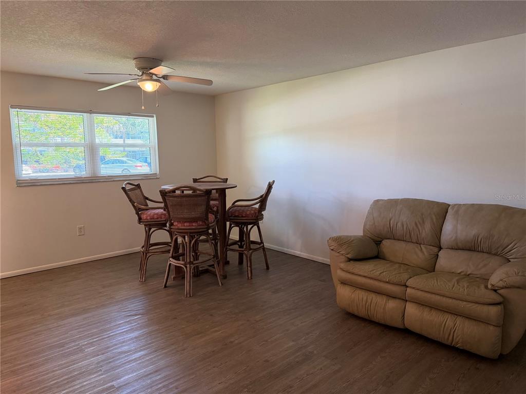 A room with wood-look flooring features a dining set and a tan leather sofa — 245 CENTER ROAD UNIT 103, VENICE, FL