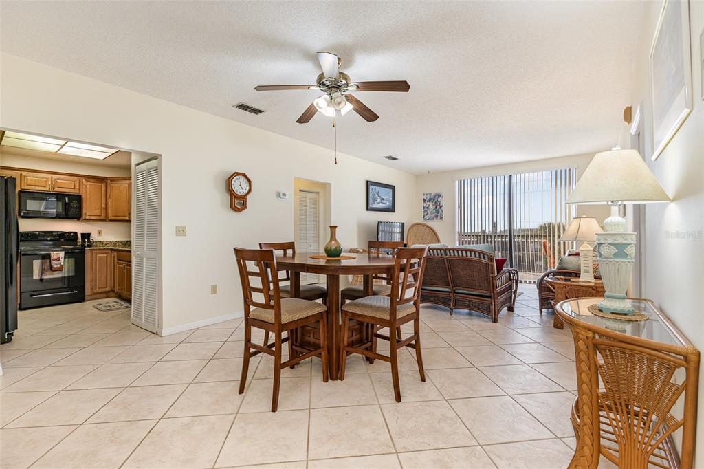An open-concept dining and living area features tile flooring, a ceiling fan, and wicker furniture — 333 N ATLANTIC AVENUE UNIT 305, COCOA BEACH, FL