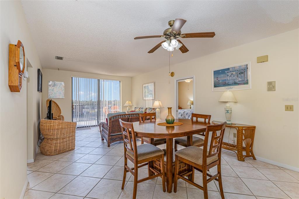 A dining area with a wooden table and chairs sits in front of a living room — 333 N ATLANTIC AVENUE UNIT 305, COCOA BEACH, FL