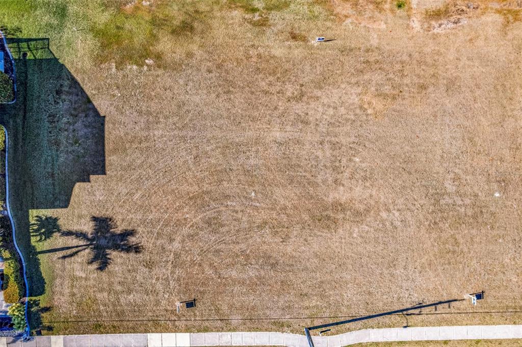 An aerial view shows a vacant, grassy residential lot next to a house with a shadow — 3639 BAL HARBOR BOULEVARD, PUNTA GORDA, FL