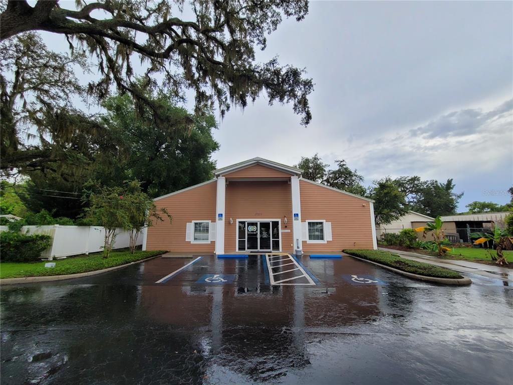 A tan, single-story commercial building features a central entrance with two white pillars and parking — 37310 PURE WATER WAY, ZEPHYRHILLS, FL