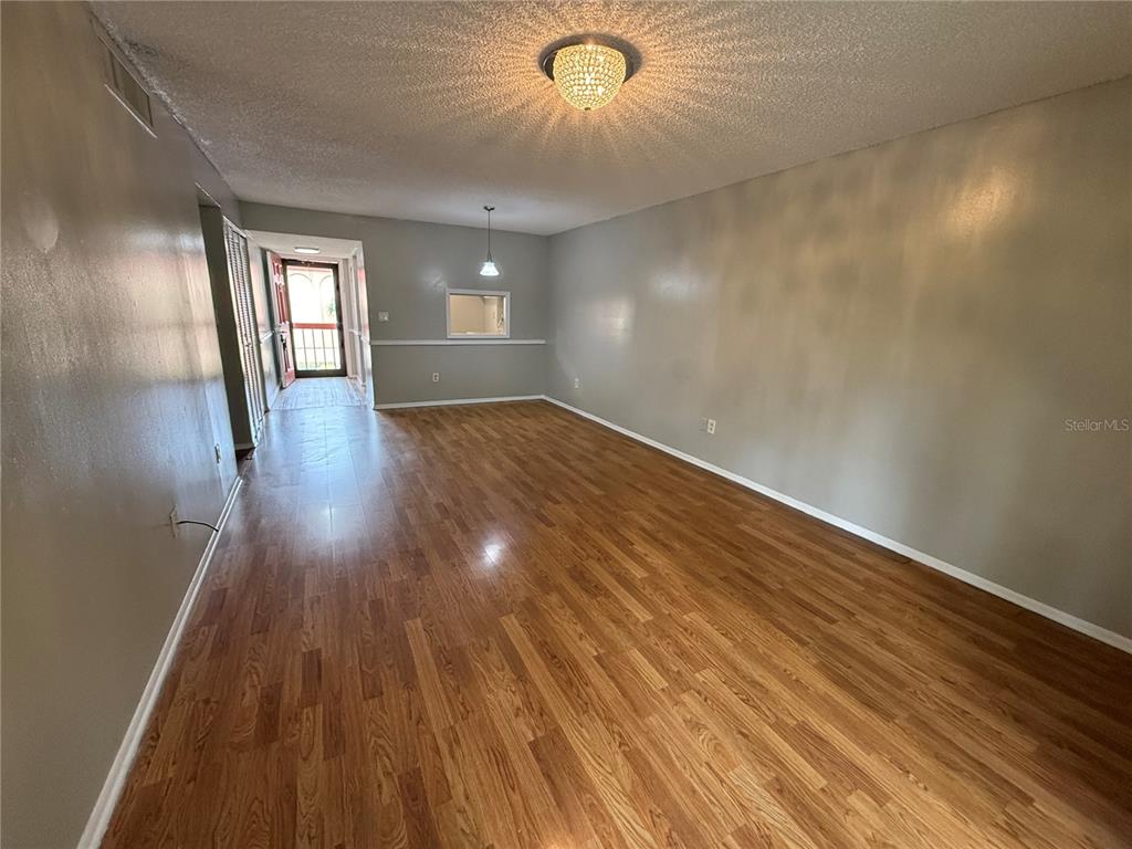 An empty living room features wood-look flooring, gray walls, and a decorative ceiling light fixture — 2800 N POWERS DRIVE UNIT 9, ORLANDO, FL