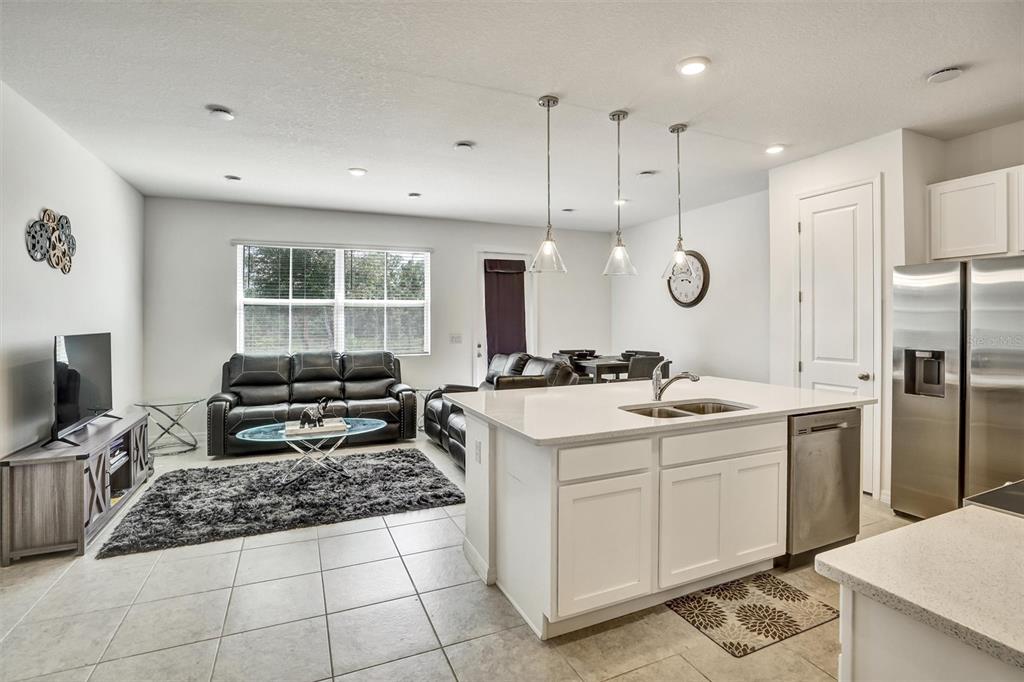 An open-concept kitchen and living area features white cabinetry, stainless steel appliances, and tile flooring — 1056 PLANTATION LANE, DAVENPORT, FL