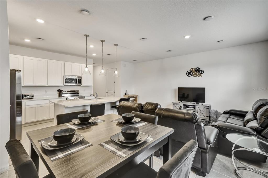 A dining area, kitchen with white cabinets, and living room with leather furniture are shown — 1056 PLANTATION LANE, DAVENPORT, FL
