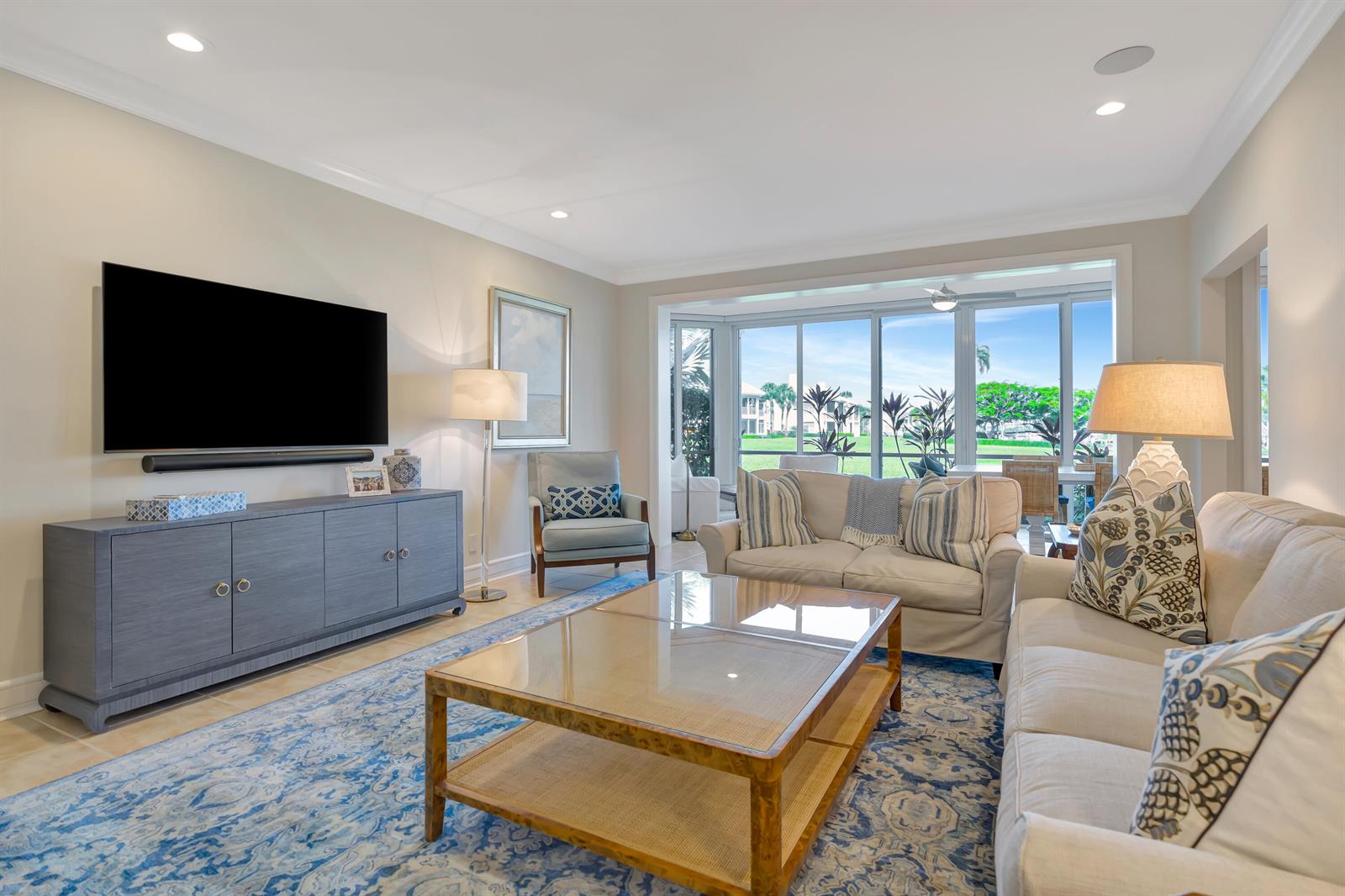 A living room features a blue media console, a glass coffee table, and large windows — 1201 Captains Way, Jupiter FL 33477, JUPITER, FL