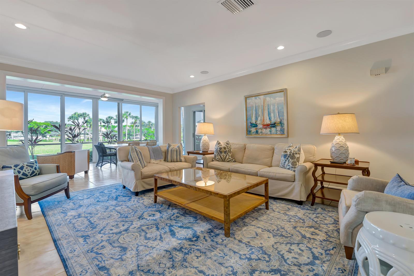 A living room features a large blue patterned rug, beige sofas, and floor-to-ceiling windows — 1201 Captains Way, Jupiter FL 33477, JUPITER, FL