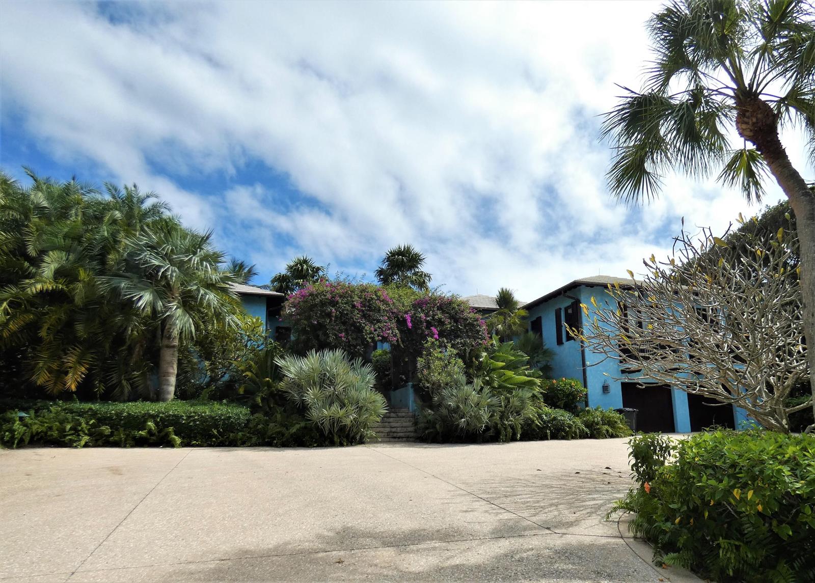 A blue two-story house with a large driveway, lush tropical landscaping, and a stone staircase — 521 S Beach Road, Jupiter Island FL 33455, JUPITER ISLAND, FL