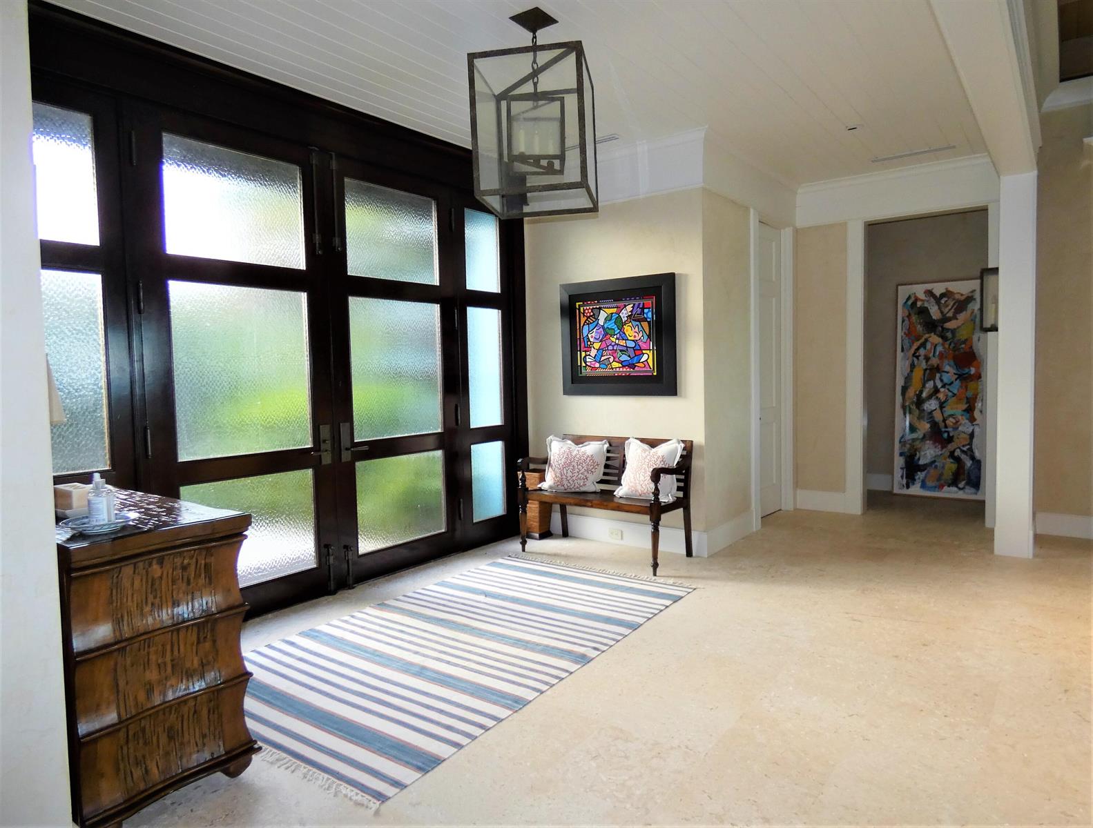 A bright entryway features a striped rug, a wooden bench, and a large glass-paneled door — 521 S Beach Road, Jupiter Island FL 33455, JUPITER ISLAND, FL