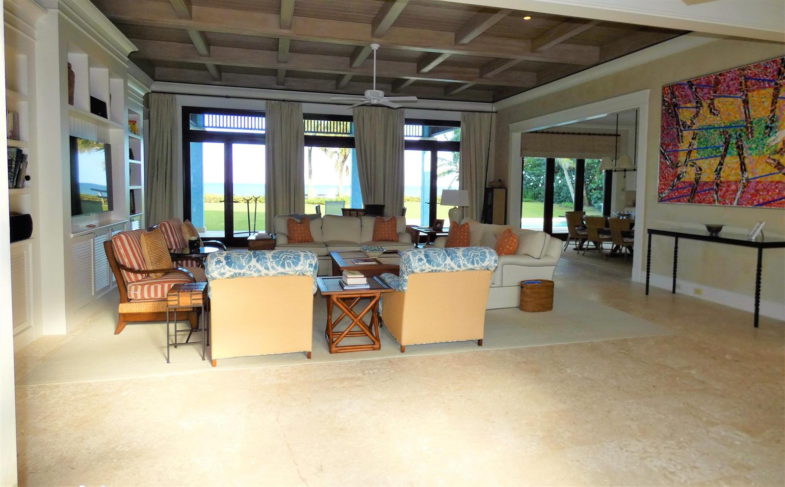A spacious living room features a coffered wood ceiling, stone floors, and views of the ocean — 521 S Beach Road, Jupiter Island FL 33455, JUPITER ISLAND, FL