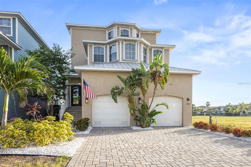 A two-story house with a beige stucco exterior, two garage doors, and a paved driveway — 1340 APOLLO BEACH BOULEVARD S, APOLLO BEACH, FL