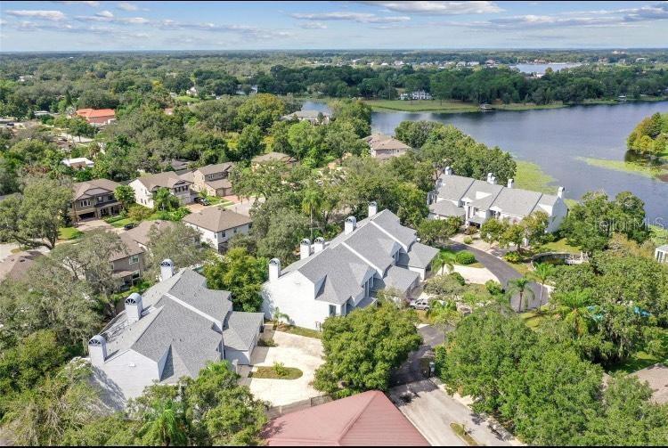 An aerial view shows several multi-story residential buildings surrounded by trees near a lake — 9726 TIFFANY OAKS LANE UNIT 9726, TAMPA, FL