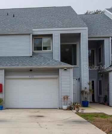 A two-story townhouse exterior features light gray siding, a white garage door, and a concrete driveway — 9726 TIFFANY OAKS LANE UNIT 9726, TAMPA, FL