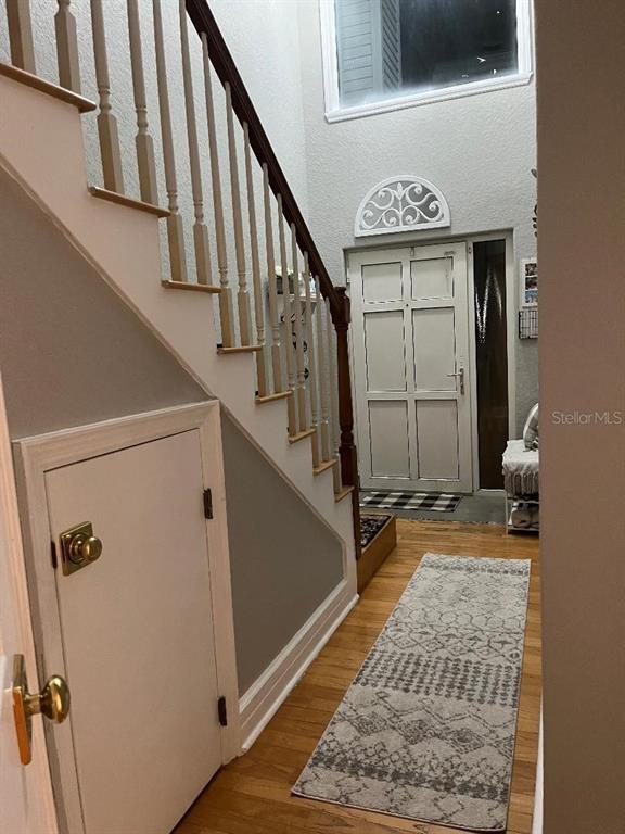 An entryway features hardwood floors, a staircase with a wooden railing, and a front door — 9726 TIFFANY OAKS LANE UNIT 9726, TAMPA, FL
