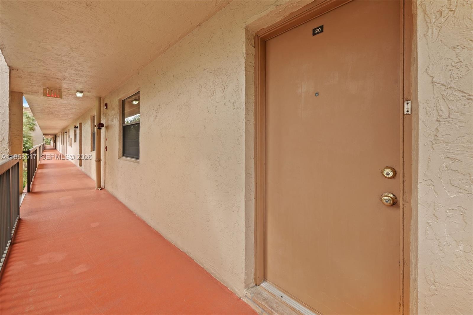 A tan apartment door numbered 310 is located along an outdoor walkway with orange flooring — 4950 E Sabal Palm Blvd # 310, Tamarac FL 33319, TAMARAC, FL