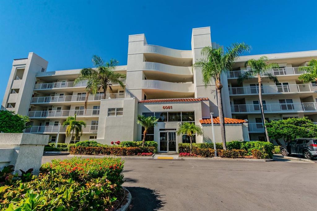 A multi-story apartment building with white balconies and palm trees stands under a blue sky — 6081 BAHIA DEL MAR CIRCLE UNIT 349, ST PETERSBURG, FL