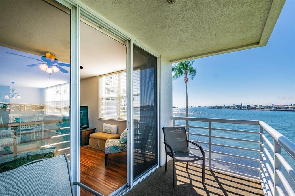 A balcony with a metal railing overlooks a body of water next to a living room — 6081 BAHIA DEL MAR CIRCLE UNIT 349, ST PETERSBURG, FL
