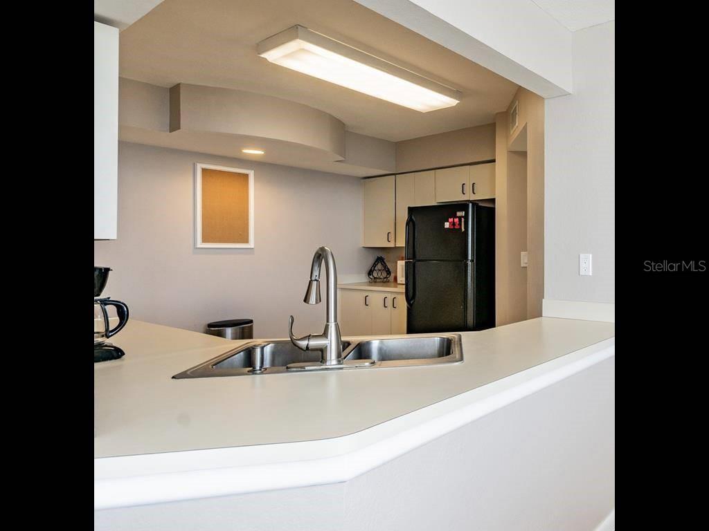 A kitchen features a breakfast bar, a stainless steel sink, and a black refrigerator — 6081 BAHIA DEL MAR CIRCLE UNIT 349, ST PETERSBURG, FL