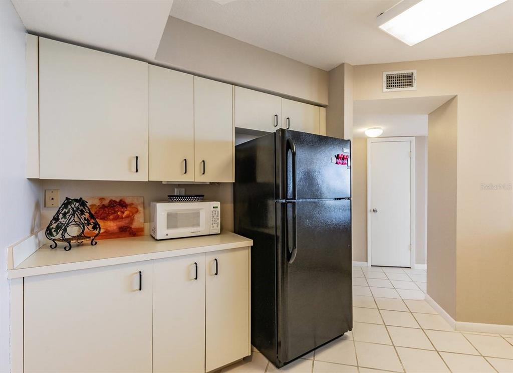 A kitchen features white cabinets, a black refrigerator, a white microwave, and tiled flooring — 6081 BAHIA DEL MAR CIRCLE UNIT 349, ST PETERSBURG, FL