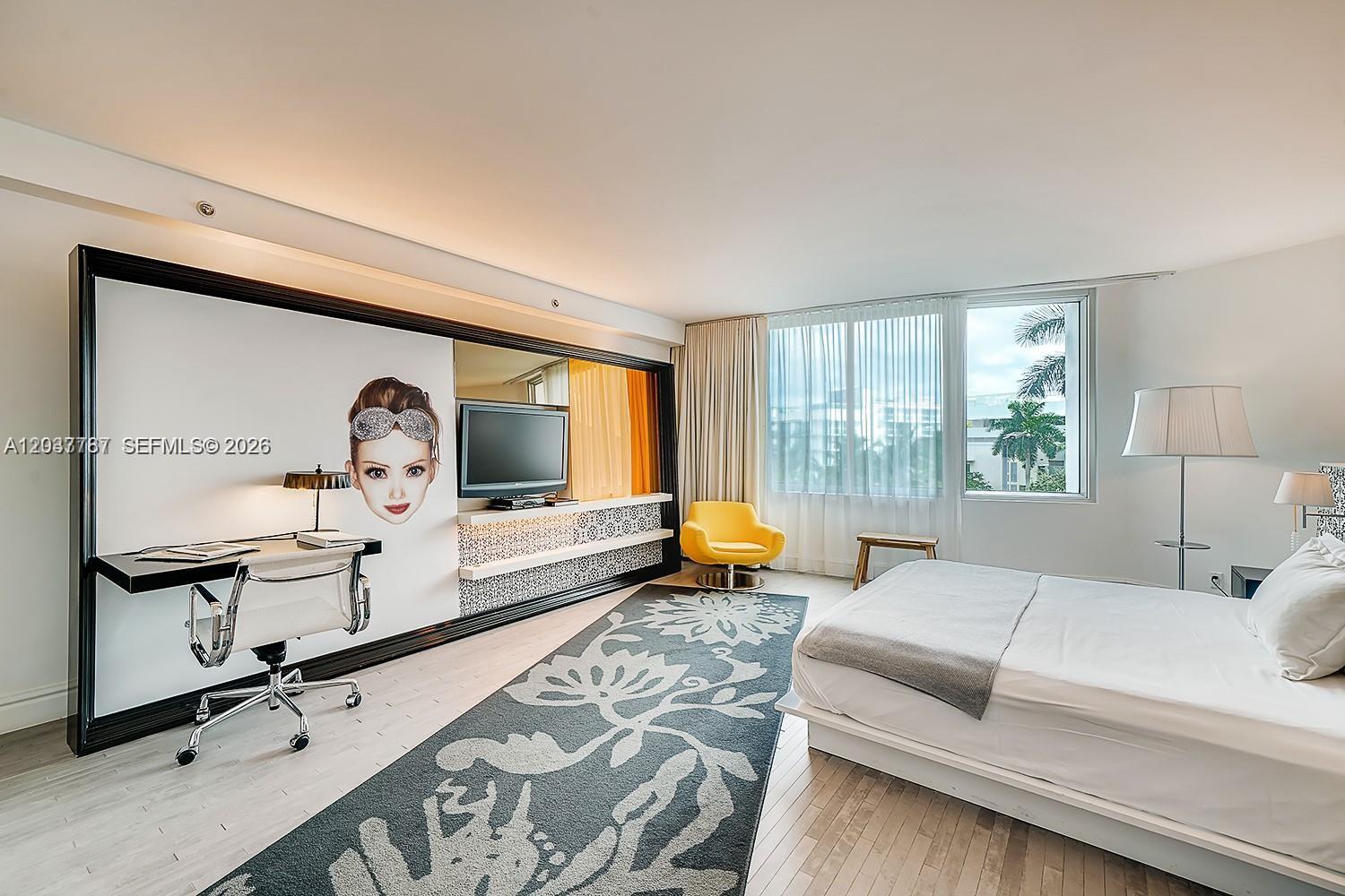 A bedroom features a desk, a yellow chair, a large patterned rug, and a bed — 1100 West Ave # 525, Miami Beach FL 33139, MIAMI BEACH, FL