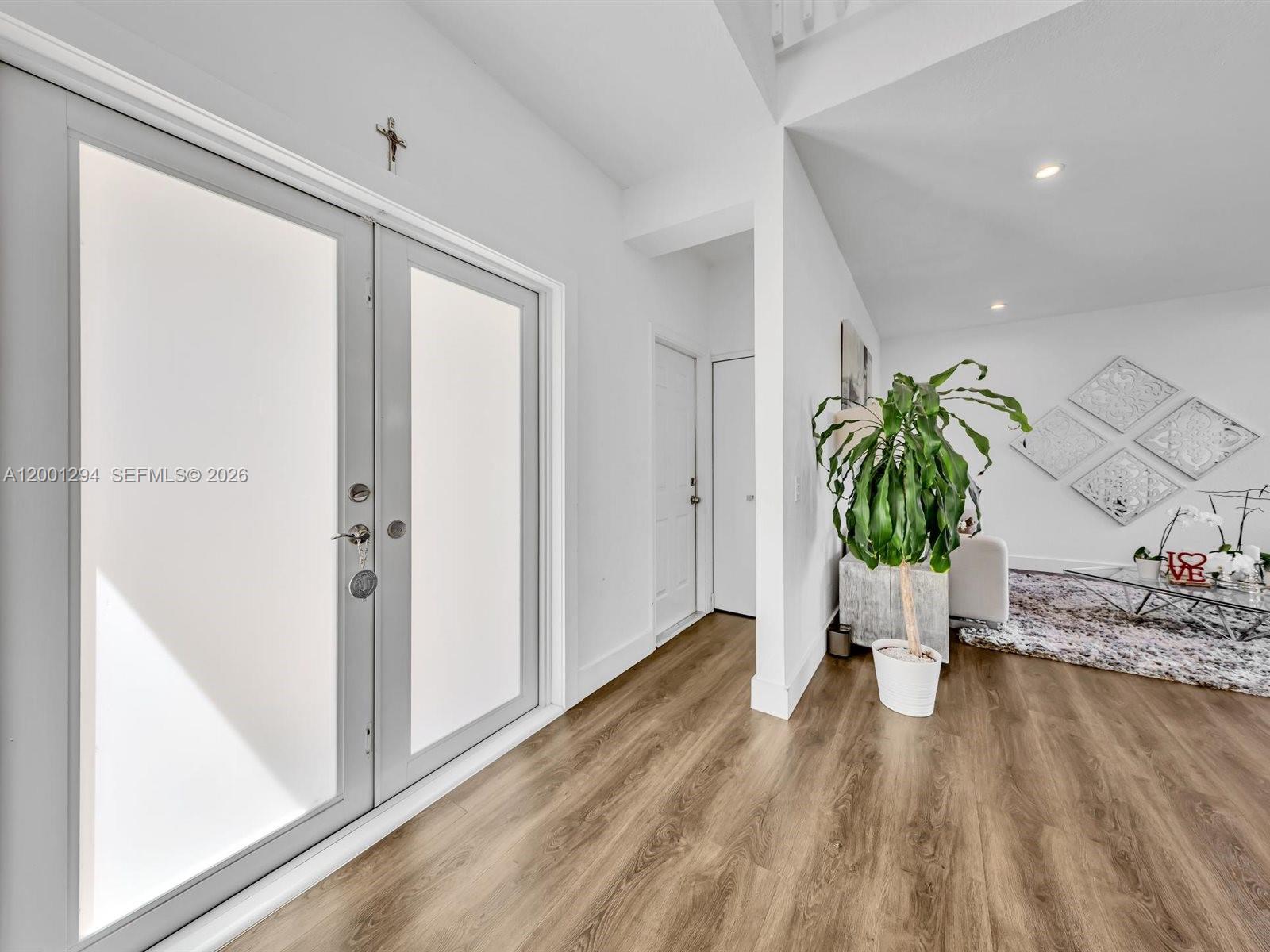 A bright entryway features light wood-look flooring, double glass doors, and a large potted plant — 1042 Thistle Creek Ct, Weston FL 33327, WESTON, FL
