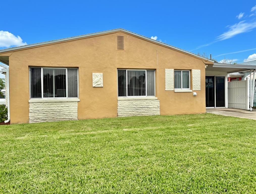 A single-story house with tan stucco walls, white stone accents, and a front lawn — 360 72ND AVENUE, ST PETERSBURG, FL