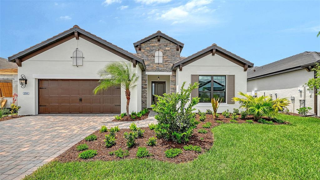 A single-story house with a stone-accented entryway, a brown garage door, and landscaped front yard — 204 TERACORSA DRIVE, NOKOMIS, FL