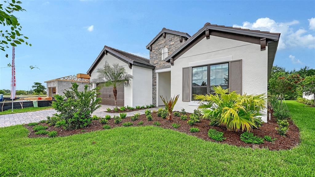 A single-story house with a white stucco exterior, stone accents, and a paved driveway — 204 TERACORSA DRIVE, NOKOMIS, FL
