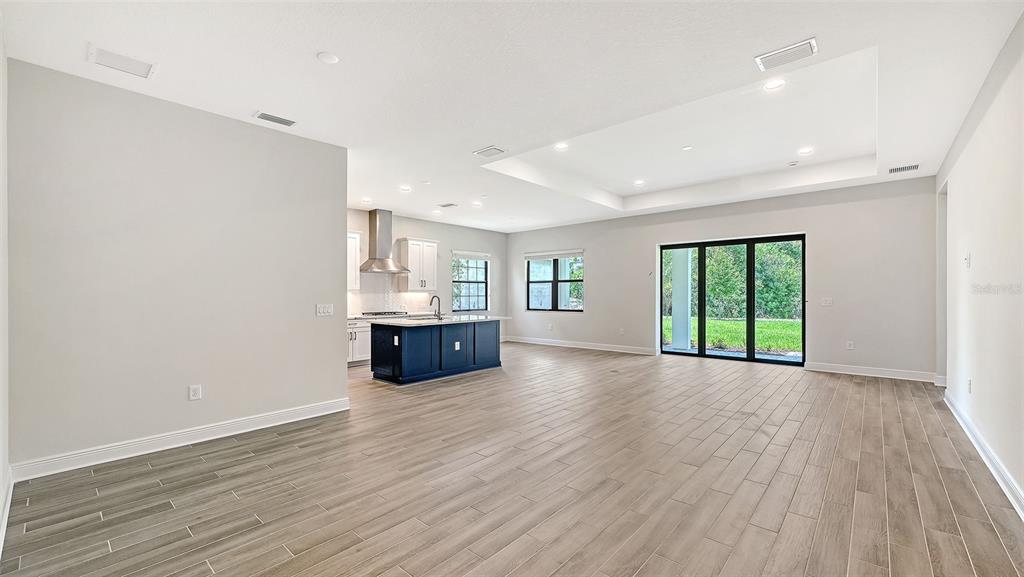 An open-concept living area features light gray walls, wood-look tile flooring, and a dark kitchen island — 204 TERACORSA DRIVE, NOKOMIS, FL