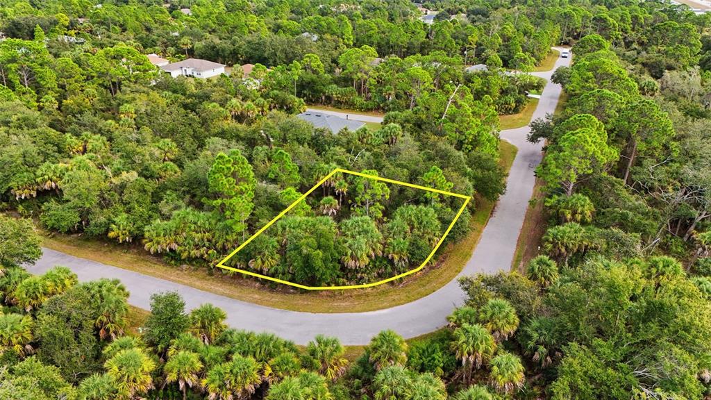 An aerial view shows a vacant, wooded residential lot outlined in yellow along a road — RAYFIELD DRIVE, NORTH PORT, FL