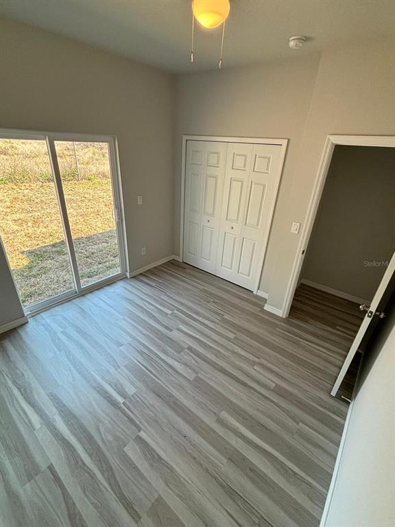 A room with light wood-look flooring, a sliding glass door, and a white closet — 1462 LAS VILLAS BOULEVARD, SEBRING, FL