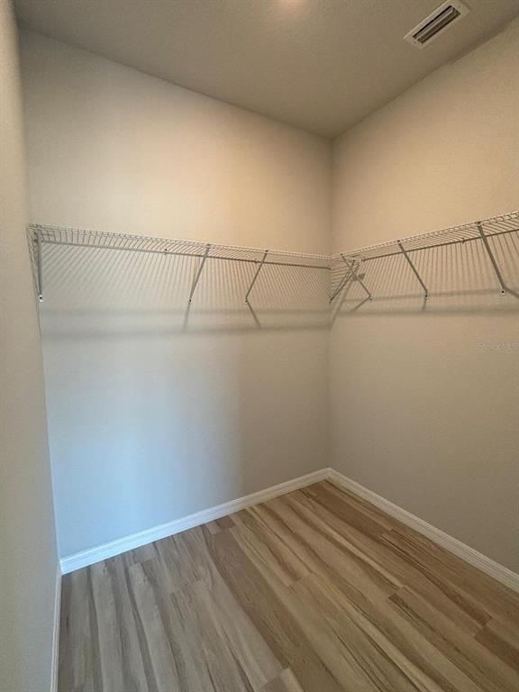 A walk-in closet features light-colored wood-look flooring and white wire shelving on the walls — 1462 LAS VILLAS BOULEVARD, SEBRING, FL