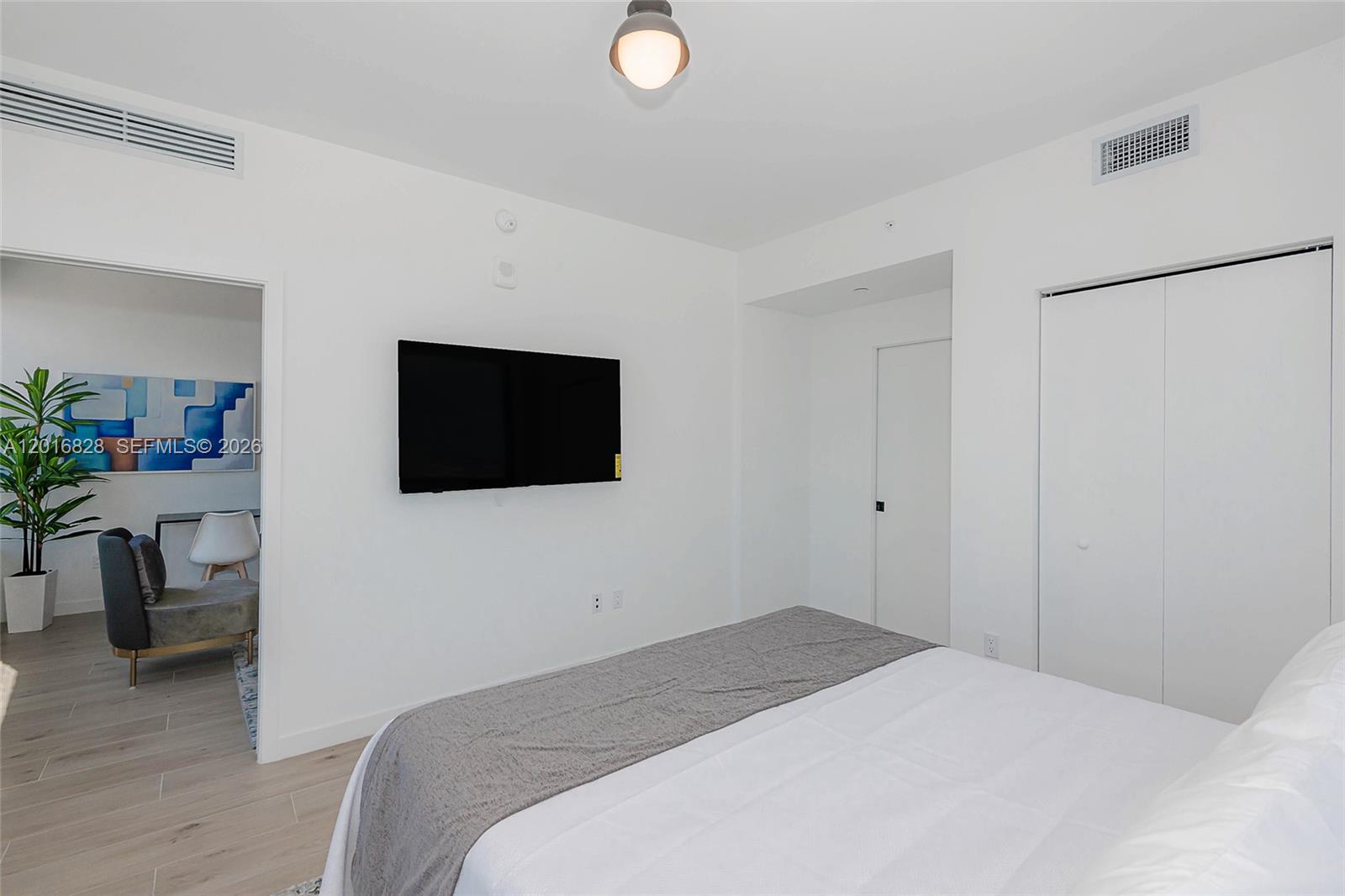 A bedroom features a wall-mounted television, a bed with a gray runner, and white walls — 225 N Miami Ave # 2801, Miami FL 33128, MIAMI, FL