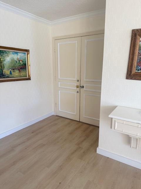 A room with light wood-look flooring, cream walls, double doors, and two framed paintings — 1180 S Ocean Boulevard # D, Boca Raton FL 33432, BOCA RATON, FL