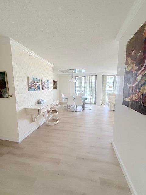 A bright living and dining area features light wood flooring, a wall-mounted desk, and balcony access — 1180 S Ocean Boulevard # D, Boca Raton FL 33432, BOCA RATON, FL