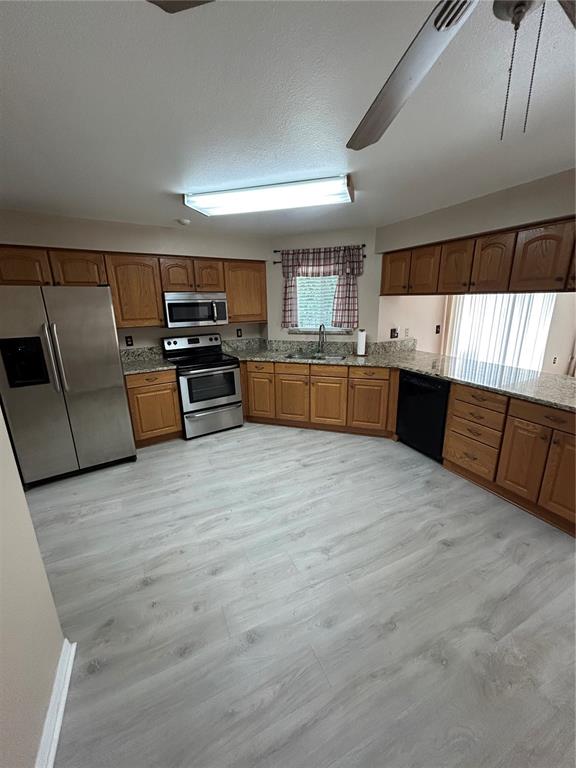 A kitchen features oak cabinets, granite countertops, stainless steel appliances, and light-colored wood-look flooring — 2410 CHOBEE COURT, LAND O LAKES, FL