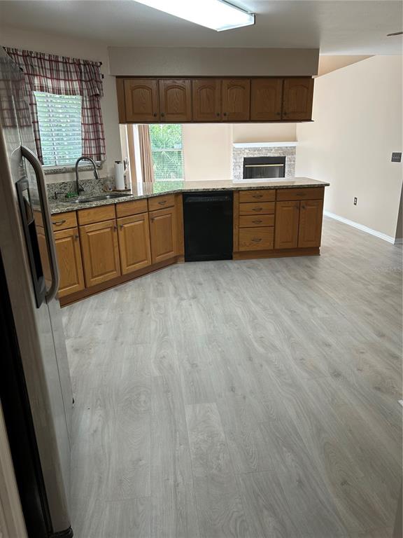 A kitchen features wood cabinets, granite countertops, a black dishwasher, and light-colored wood-look flooring — 2410 CHOBEE COURT, LAND O LAKES, FL