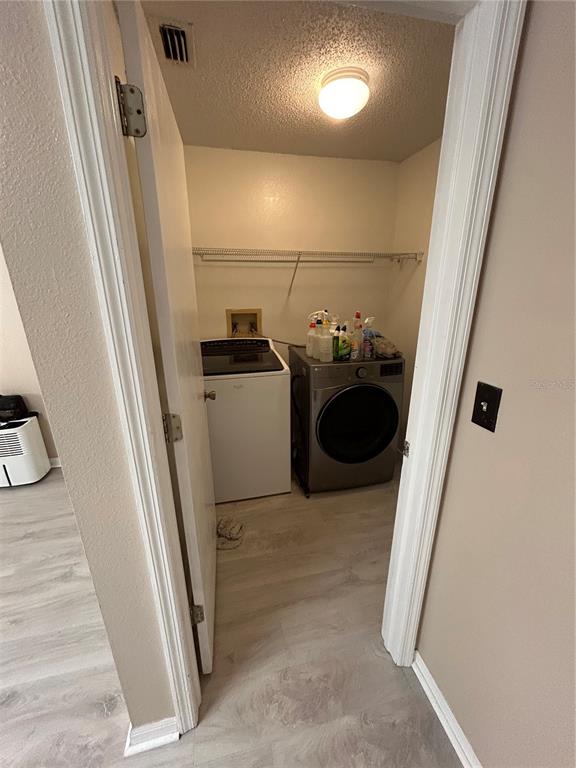 A laundry closet contains a white top-load washer and a stainless steel front-load dryer — 2410 CHOBEE COURT, LAND O LAKES, FL