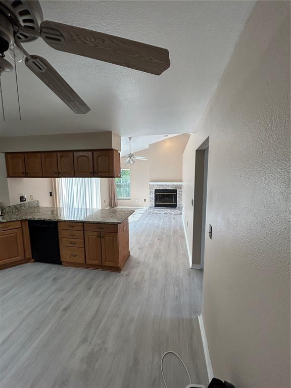 A kitchen with wood cabinets and granite countertops opens into a living room with fireplace — 2410 CHOBEE COURT, LAND O LAKES, FL
