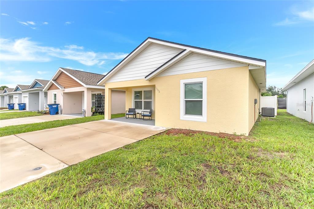 A yellow single-story house with a concrete driveway and a covered front porch — 1502 LAS VILLAS BOULEVARD, SEBRING, FL